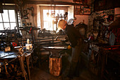 Female blacksmith working at anvil in workshop