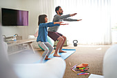 Father and daughter exercising in living room