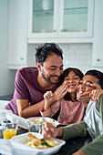 Playful family eating take out food in kitchen