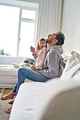 Playful father and daughter eating popcorn on sofa