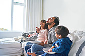 Playful family eating popcorn on sofa