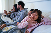 Portrait happy girl eating popcorn on sofa