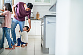 Affectionate boy hugging leg of father in kitchen