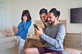 Father and kids using smart phone in living room