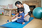 Mother and son on yoga mat in living room