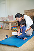 Son showing mother drawing on yoga mat