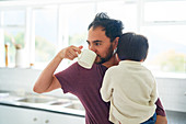 Man drinking coffee and holding son