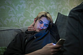 Teenage boy using smart phone on sofa