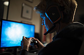 Boy with headset playing videogame in dark room