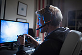 Boy with headset playing videogame at computer
