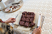 Woman cutting fresh baked brownies on cooling rack