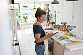 Woman with smart phone cooking