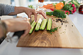 Woman slicing fresh cucumbers on cutting board