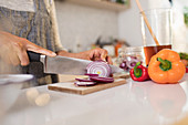 Close up woman slicing red onions on cutting board