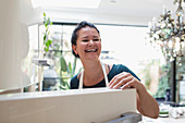 Happy woman laughing at open refrigerator