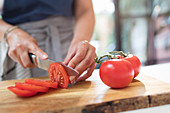 Woman with knife slicing red tomatoes