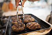 Woman grilling hamburgers on kitchen stove