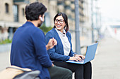 Business people working at laptop on boardwalk