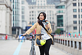 Woman with smart phone walking bicycle