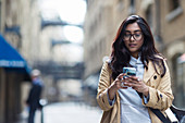 Woman using smart phone on city street