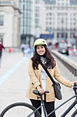 Portrait businesswoman with bicycle on city bridge