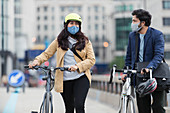 Business people in face masks walking bicycles