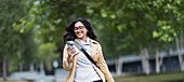 Smiling woman using smart phone in park