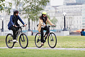 Business people riding bicycles in city park