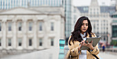 Businesswoman using digital tablet on city bridge