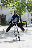 Playful businessman riding bicycle