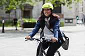 Happy woman in helmet riding bicycle on sidewalk