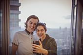 Happy couple taking selfie at highrise window