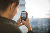 Woman with camera phone photographing sunset