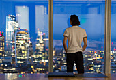 Businessman at highrise window, London, UK