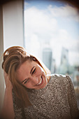 Businesswoman laughing with hand in hair at window