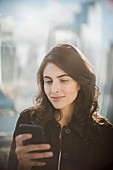 Businesswoman using smart phone at window