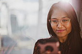 Businesswoman using smart phone at sunny window