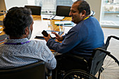 Businessman in wheelchair talking with colleague
