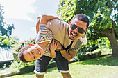 Portrait playful father and son in sunny backyard