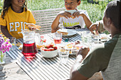 Family eating lunch at sunny summer patio table