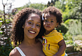 Portrait happy mother and toddler daughter in yard