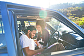Happy couple laughing on road trip in sunny car