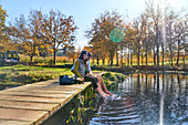 Couple on dock dipping bare feet in autumn lake