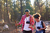 Couple hiking with binoculars and camera in woods