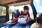 Couple laughing on road trip at back of car