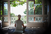 Serene woman meditating at tranquil balcony window