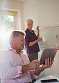 Senior couple with tablet talking in kitchen