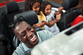 Happy man laughing in convertible with family