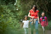 Mother and daughters hiking on trail in woods