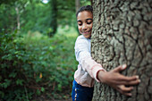 Cute girl hugging tree trunk in woods